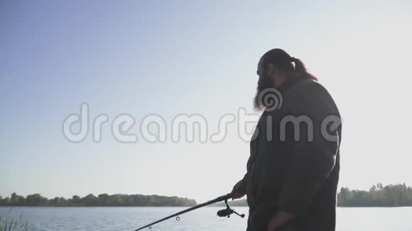 有胡子的人正在河岸上钓鱼在河里用鱼竿钓鱼的渔夫河里钓鱼慢视频的预览图