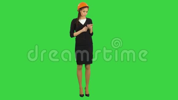 戴着头盔的年轻女建筑师在绿色屏幕上打电话Chroma键视频的预览图