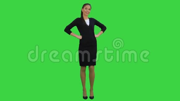 漂亮的女商人站着双手叉腰对着绿色屏幕上的摄像机微笑Chroma键视频的预览图