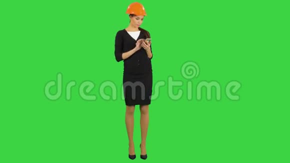 戴头盔的女工程师用手机在绿色屏幕上拍摄施工照片彩色键视频的预览图