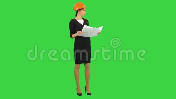 年轻女主管戴着头盔拿着蓝图在绿色屏幕上检查建筑Chroma键视频的预览图