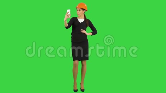年轻的女建筑师戴着头盔在绿色屏幕上打电话自拍Chroma键视频的预览图