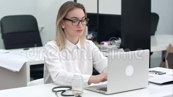 年轻女子集中精力在办公室桌上的笔记本电脑上打眼镜视频的预览图