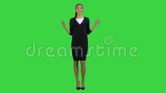微笑着穿着正式服装的年轻女子对着镜头说话在绿色屏幕上打手势Chroma键视频的预览图