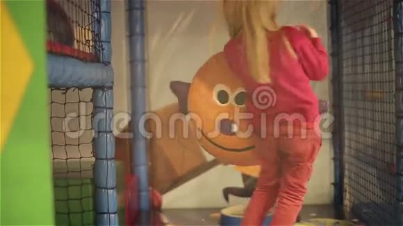 小女孩微笑着摇动有趣的球小美丽的女孩在儿童游戏室里玩视频的预览图