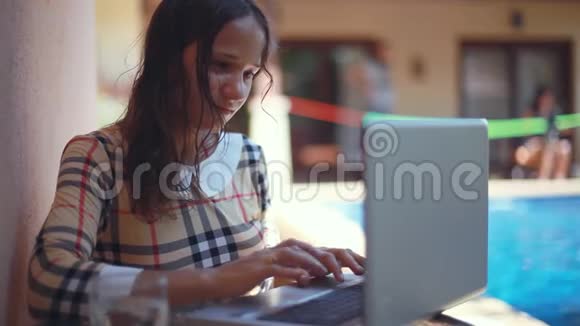 坐在池边的女人在用她的笔记本电脑美丽的年轻女性自由职业者接受采访视频的预览图