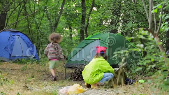 两个孩子在森林帐篷附近的空地上玩耍视频的预览图