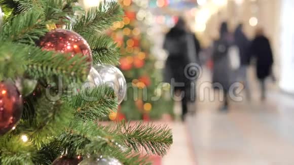 商场里喜庆的气氛在前景的圣诞杉不在焦点的人走路和买礼物视频的预览图