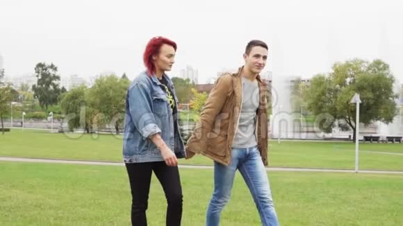 年轻的幸福夫妇牵着手在城市公园散步视频的预览图