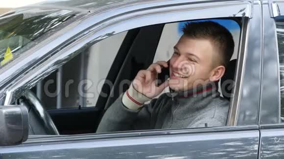 快乐的年轻人在路上停车用手机说话开车的商人在智能手机上讲话视频的预览图