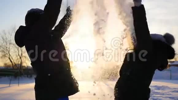 一个男人和一个女孩把雪扔到头上拥抱在日落的背景上视频的预览图