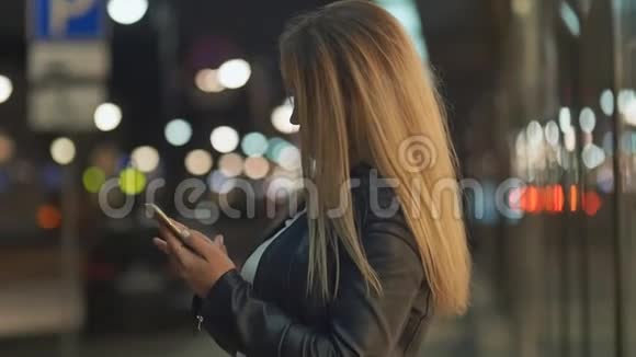 金发少女晚上在城里用手机视频的预览图