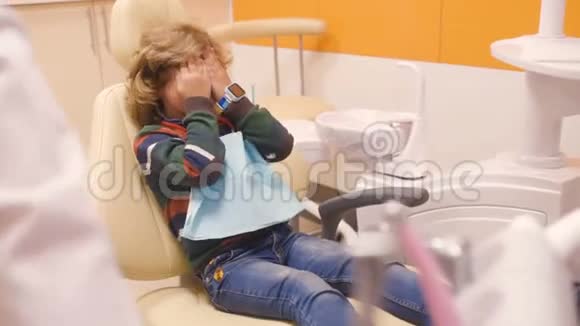 卷发的孩子在牙科椅上放纵和鬼脸视频的预览图