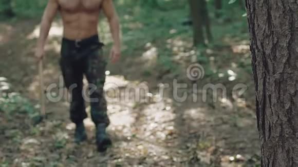 一幅英俊的胡须男在森林里拿着斧头走路的肖像慢慢地视频的预览图