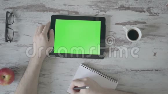 男性手在笔记本上做笔记其次是一个绿色屏幕的平板电脑视频的预览图