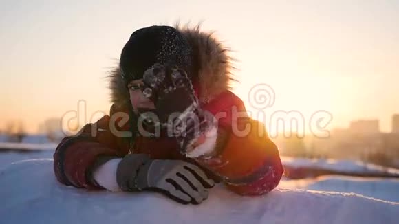 一个孩子在冬天的公园里挥手在夕阳的背景下冬天的雪景日落时间视频的预览图