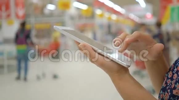 女性使用平板电脑在超市手特写视频的预览图