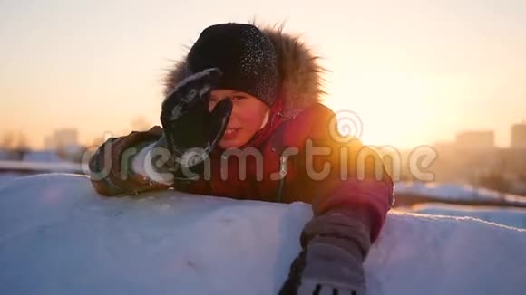 一个孩子在冬天的公园里挥手在夕阳的背景下冬天的雪景日落时间视频的预览图