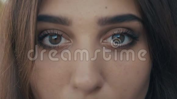 美丽的年轻女子黑发模特的特写眼睛看着镜头大眼睛的女孩视频的预览图