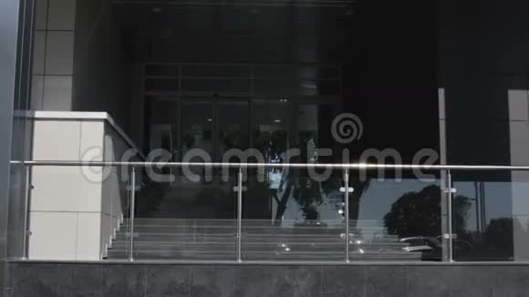 那个穿着灰色西装和太阳镜的商人正出现在商务中心的门廊上视频的预览图