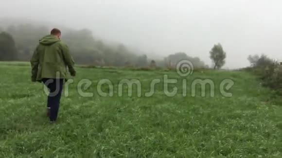 在雾蒙蒙的早晨男人走在草地上视频的预览图