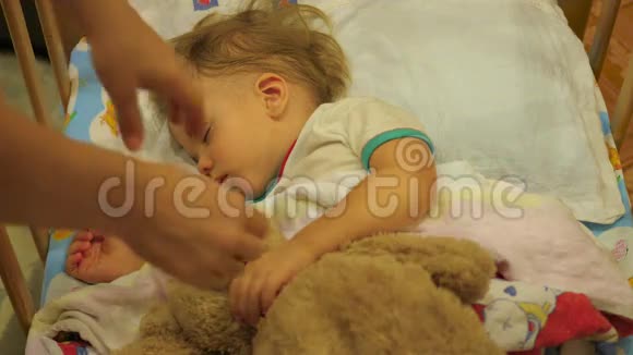 这个可爱的婴儿和一只泰迪熊睡在一张小床上妈妈搬玩具熊视频的预览图
