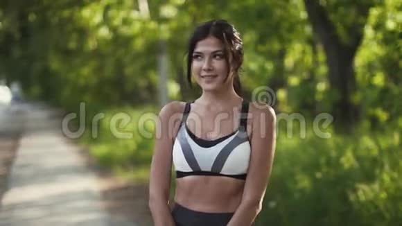 一位年轻漂亮的女运动员的肖像模特穿着运动服摆出相机和微笑视频的预览图