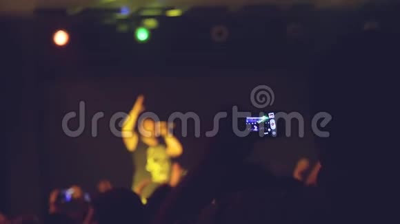 在音乐会晚会上歌迷们用手机拍摄视频和照片为摇滚音乐活动欢呼视频的预览图