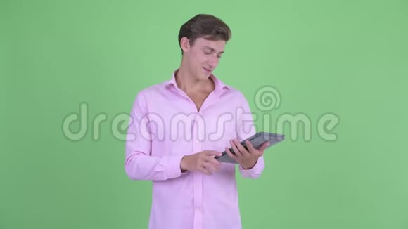 快乐年轻英俊的商人用数码平板电脑说话视频的预览图
