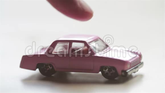 用手指把一辆粉红色的玩具车推到车架上视频的预览图
