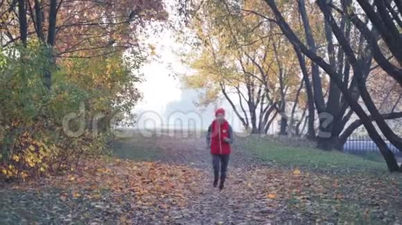 早晨在浓雾中在城市公园慢跑一位年轻女子任何天气概念下的健康生活方式视频的预览图