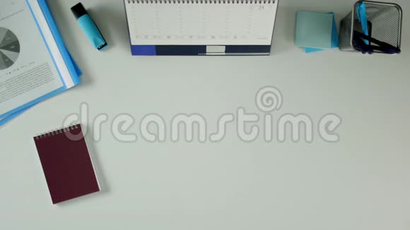 一个男人坐在办公桌前拿着笔记本写下是这个词桌子上有办公用品视频的预览图