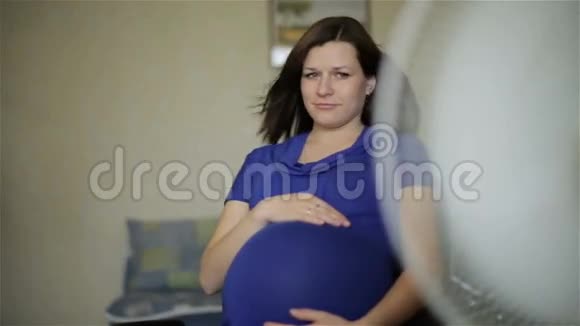 孕妇正在抚着坐在扇子前的大肚子视频的预览图