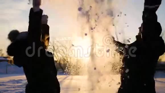 一个男人和一个女孩把雪扔到头上拥抱在日落的背景上视频的预览图