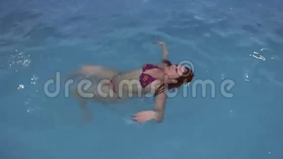 布鲁内特女孩在游泳池里游泳视频的预览图