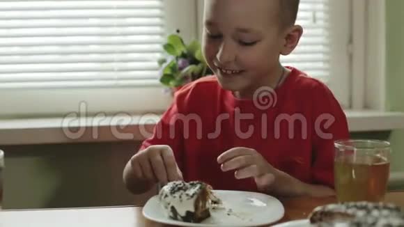 一个留着短发的小男孩把一块蛋糕放进嘴里喝茶视频的预览图