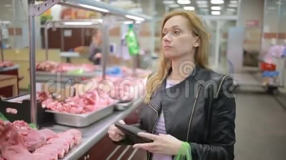 一位女士在一家超市的柜台旁边买肉看着镜头视频的预览图