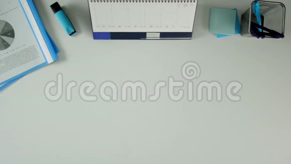 一个男人坐在办公桌前拿着笔记本写下是这个词桌子上有办公用品视频的预览图