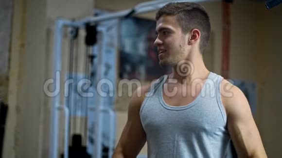 在健身房里一个男人看着镜子用肌肉发达的手臂摆动视频的预览图
