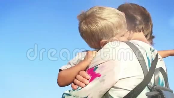 母亲怀抱中的小男孩对抗蓝天美丽的镜头耀斑慢动作视频的预览图