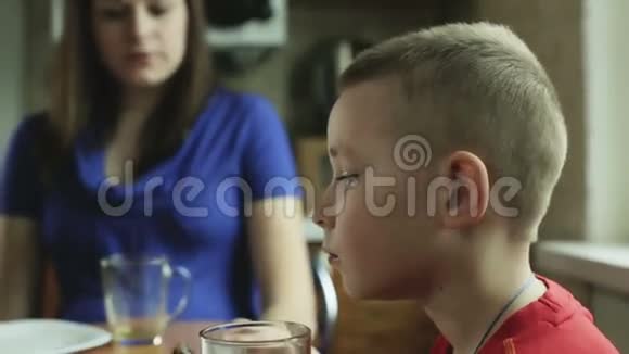 短头发的小男孩正在吃蛋糕和喝茶视频的预览图