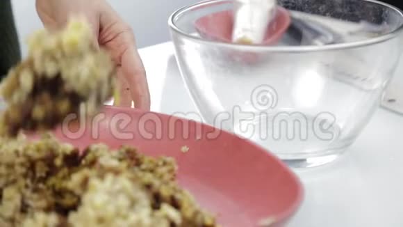女人把坚果和干果混合在玻璃碗里烹饪健康食品视频的预览图