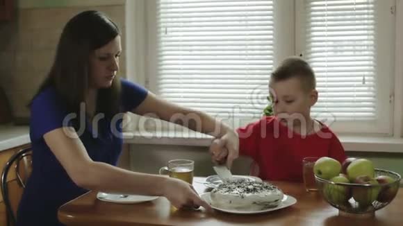 母亲和儿子一起在切蛋糕把切片放在盘子里视频的预览图