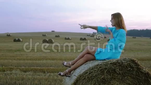 美丽的年轻女子坐在干草堆上跳舞视频的预览图