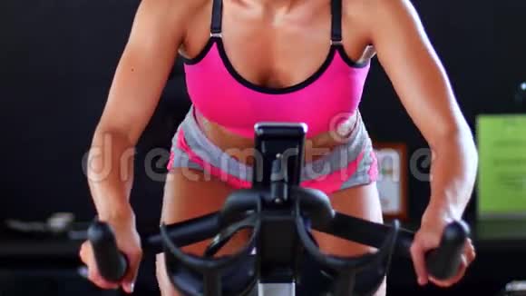 女孩在健身房骑着固定自行车做运动视频的预览图