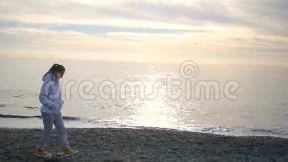 金发碧眼的女人穿着白色夹克在海边散步视频的预览图