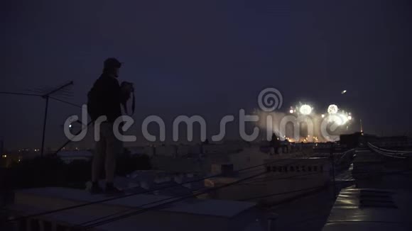 年轻的摄影师站在楼顶对着镜头拍摄烟火视频的预览图