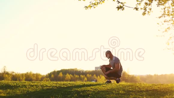 年轻的运动运动员做伸展运动准备在公园锻炼日落色调视频视频的预览图