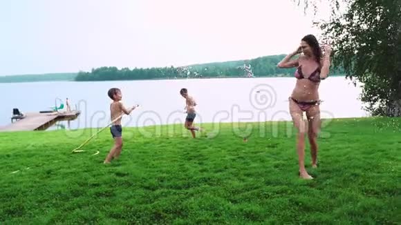 妈妈和儿子在草坪上玩耍倒着水笑着在操场上玩草地上的背景是视频的预览图