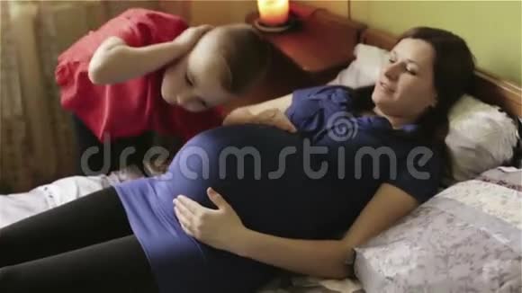 小男孩正听着大肚子的孕妈捂着第二只耳朵的手视频的预览图